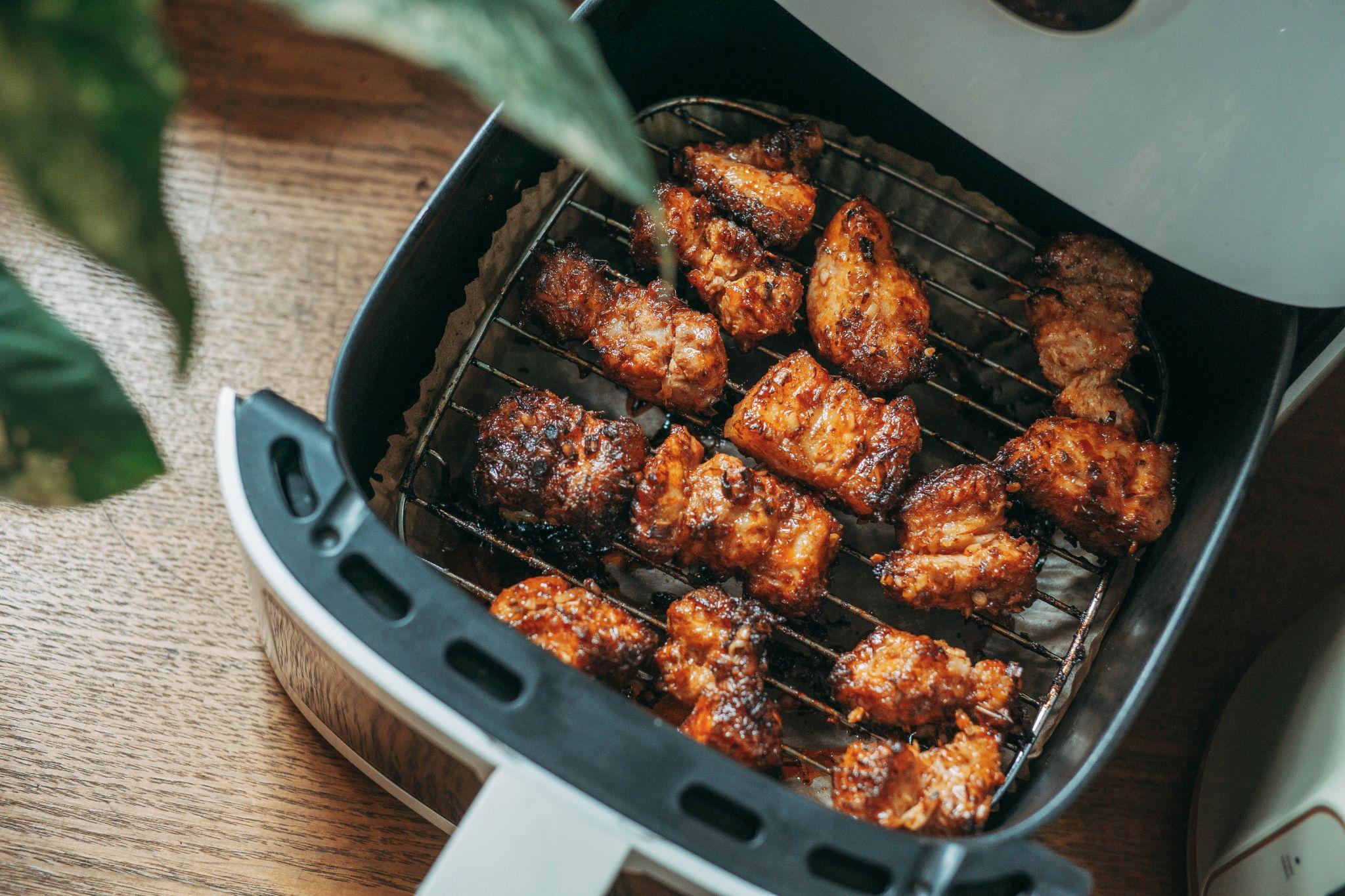 Trozos de pollo asado y crujiente dentro de la rejilla de una freidora de aire