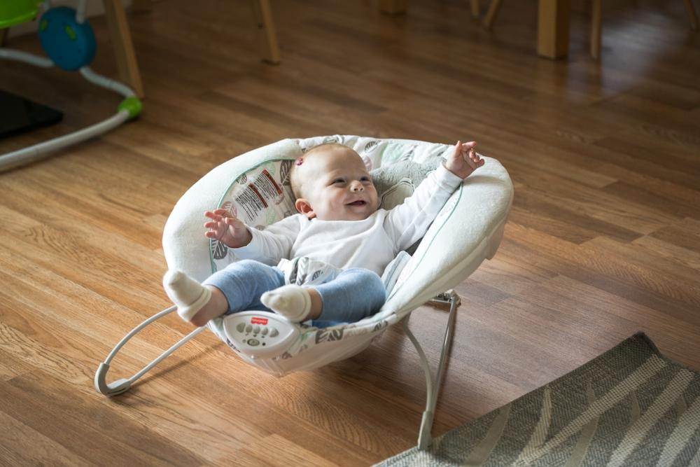 Bebe sonriente y activo en una mecedora reclinable en el salon